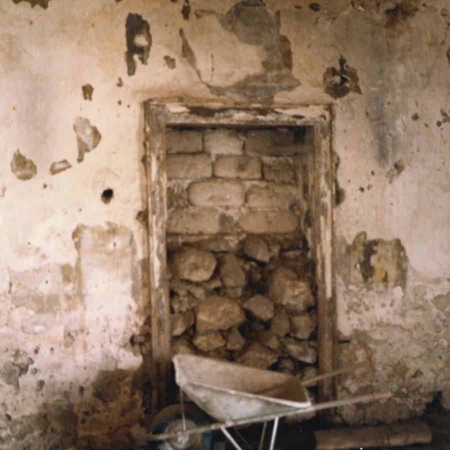Interno con finestra murata e macerie